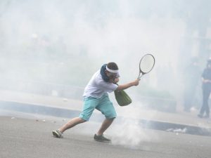 A protester returns tear gas with a tennis racket, during a protest against the government's labour market reforms in Paris, on May 26, 2016. The French government's labour market proposals, which are designed to make it easier for companies to hire and fire, have sparked a series of nationwide protests and strikes over the past three months. AFP PHOTO / ALAIN JOCARD / AFP PHOTO / ALAIN JOCARD